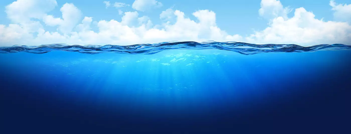 a half-half image over the oceans surface. The blue sky with clouds abbove, clear blue water below